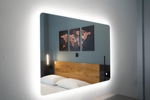 a mirror reflecting a bed with three pictures on the wall at Agora Apartments in Mytilini