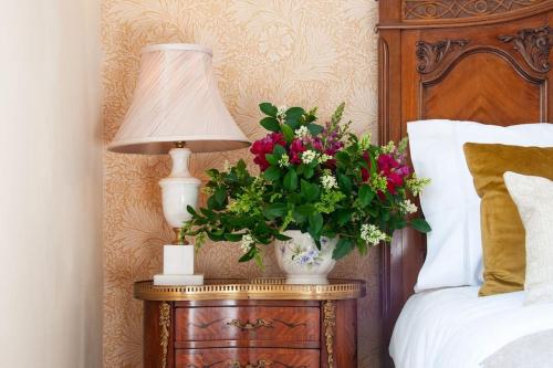 a lamp on a table next to a bed with flowers at 2 bedroom house in Chichester near Goodwood and Wittering beaches in Chichester