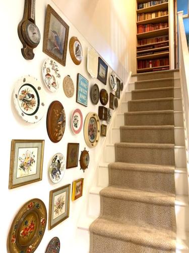 a staircase with plates and pictures on a wall at 2 bedroom house in Chichester near Goodwood and Wittering beaches in Chichester