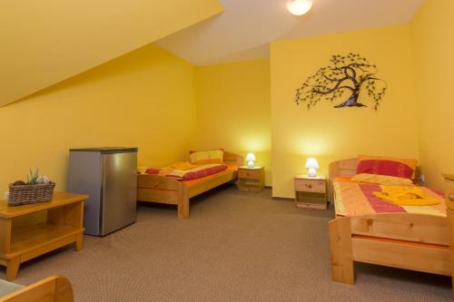 two beds in a room with yellow walls at Penzion U Černého čápa in Lasenitz