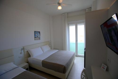 a bedroom with two beds and a tv and a window at San Marco in Marotta