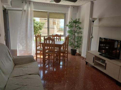 ein Wohnzimmer mit Tisch und Stühlen und einem Fernseher in der Unterkunft Apartamento en Playa de Bellreguard in Bellreguart