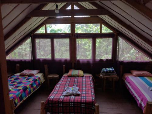 a attic room with two beds and windows at Paraiso Verde in Chijoú
