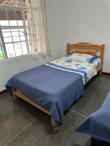 a bedroom with a bed with a blue blanket on it at El Patriarca Hotel in Sasaima