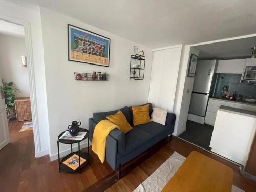 un salon avec un canapé bleu avec des coussins jaunes dans l'établissement Charming apartment 40 m2, 10th, à Paris