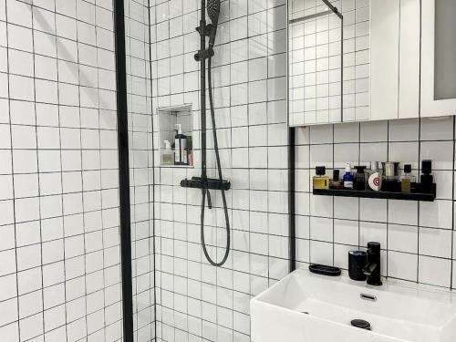 une salle de bain carrelée blanche avec une douche et un lavabo dans l'établissement Appartement Art Bougee Montmartre, à Paris