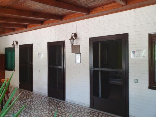three doors on the side of a white brick wall at Vila Balkan in Kikinda