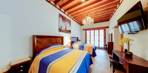 a bedroom with two beds and a flat screen tv at La Casa Baez in Pátzcuaro