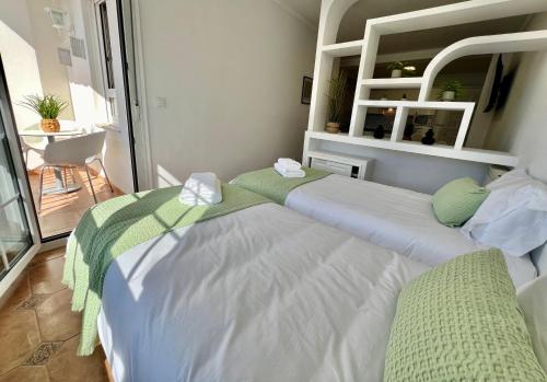 a room with three beds with green and white sheets at Balnea Baiona in Baiona