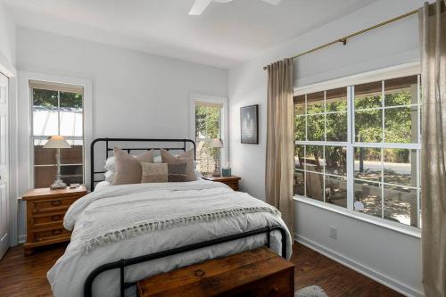 een witte slaapkamer met een groot bed en ramen bij Revins Haus - Fire Pit & Walk to Main St in Fredericksburg