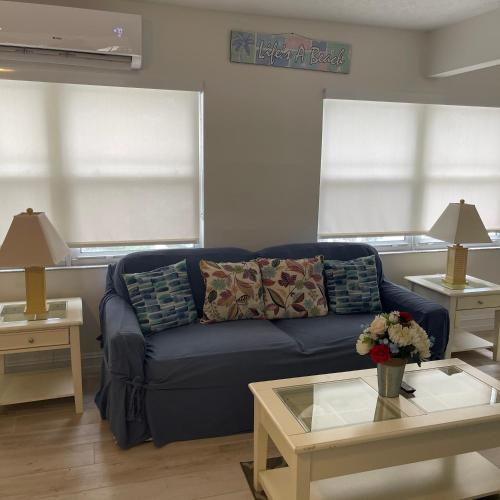 a living room with a blue couch and two windows at Kings Kamp in Key Largo