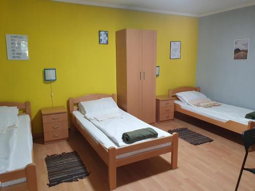 two beds in a room with yellow walls at Vila Balkan in Kikinda