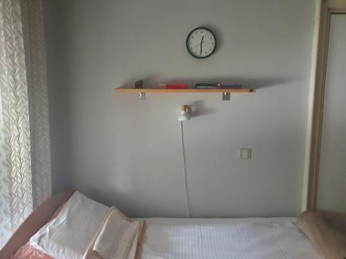 a bedroom with a bed and a clock on the wall at Vila Balkan in Kikinda