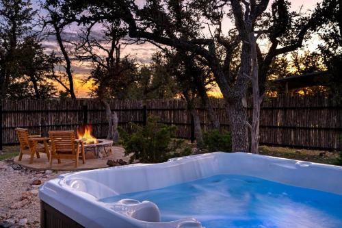a hot tub in a backyard with a fire pit at Rockin' R - Rustic Star Cabin in Fredericksburg