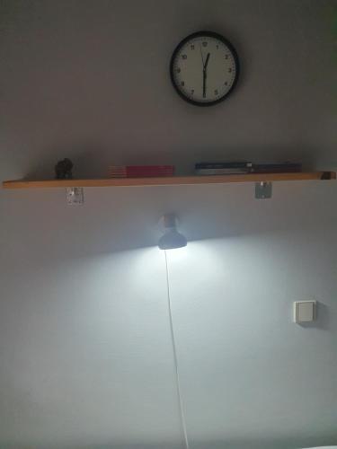 a shelf with a clock on the wall and a lamp at Vila Balkan in Kikinda