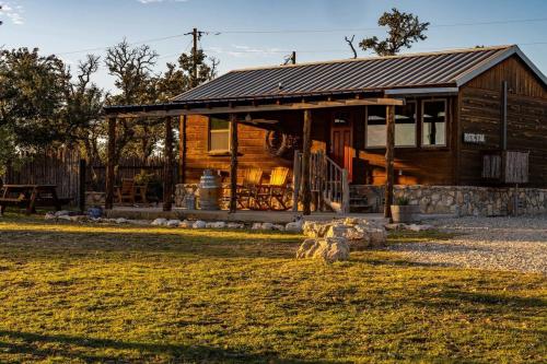 a wooden cabin with a grass field in front of it at Rockin' R - Rustic Star Cabin in Fredericksburg