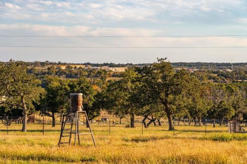 an old water tower in a field with trees at Rockin' R - Rustic Star Cabin in Fredericksburg