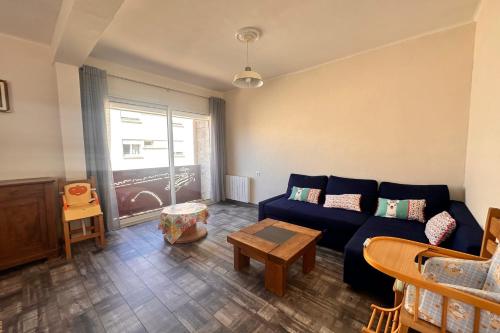 un salon avec un canapé bleu et une table dans l'établissement COEUR DE CAMARGUE - Terrasse et Garage proche de la Plage, au Grau-du-Roi