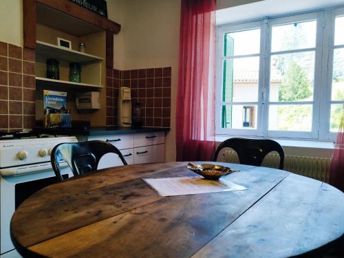a kitchen with a wooden table with chairs and a window at Charmant studio tout équipé in Olliergues