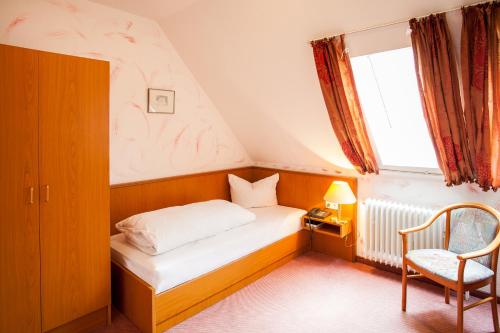 a bedroom with a bed and a chair and a window at Hotel Alter Wolf in Wolfsburg