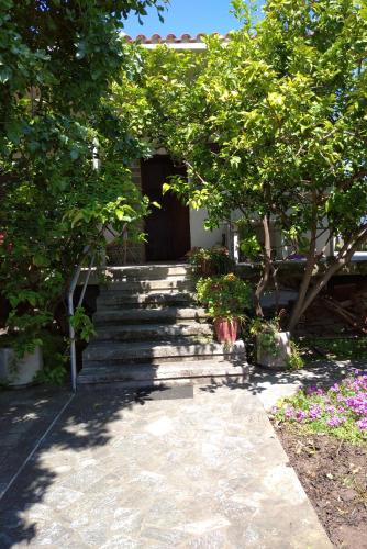 a stone walkway with trees and flowers in front of a building at The Lemon House by The Sea in Áyioi Apóstoloi