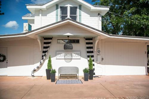 a white house with a chair in front of it at Stonewall Main Haus - Sleeps 6 in Stonewall