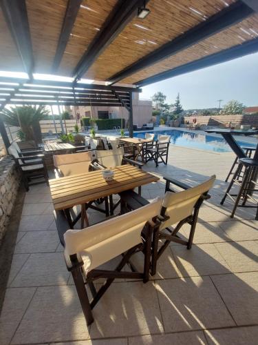 a patio with wooden tables and chairs and a pool at Petradi in Livadi