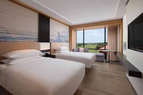 a hotel room with two beds and a television at Courtyard by Marriott Goa Colva in Colva
