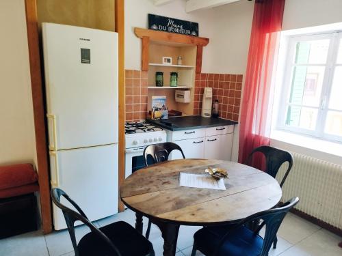 a kitchen with a wooden table and a white refrigerator at Charmant studio tout équipé in Olliergues