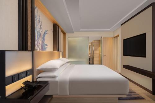 a bedroom with a white bed and a flat screen tv at Courtyard by Marriott Goa Colva in Colva