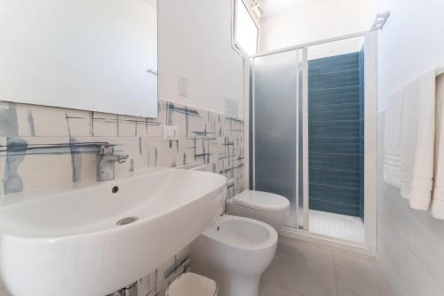 a white bathroom with a sink and a toilet at Villa Gioiello CENTRO in Favignana