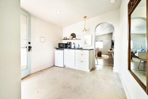 cocina con armarios blancos y espejo en The Cape - Guesthouse & Backhouse, en Fredericksburg