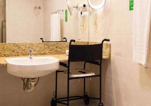 a bathroom with a sink and a chair under a mirror at Master Gramado Hotel - Espaço Kids Incrível in Gramado