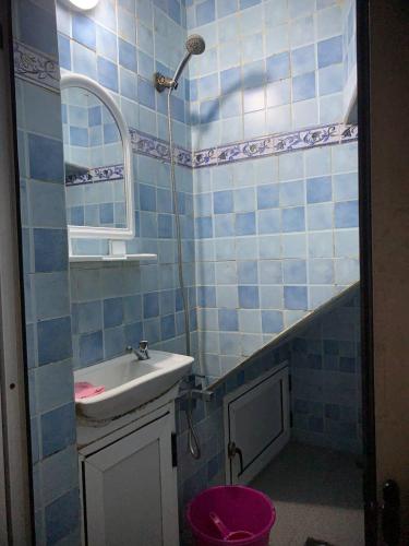 a blue tiled bathroom with a sink and a shower at Blue heart in Chefchaouen