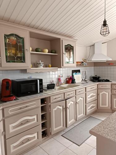 une cuisine avec des armoires blanches et un micro-ondes dans l'établissement Maison à la Brée, à La Brée-les-Bains