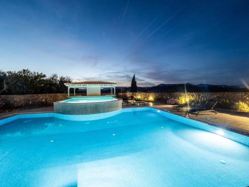 a large blue swimming pool at night with a gazebo at Villa Althea 1 in Kompítsion