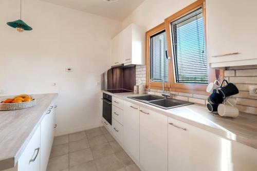 a kitchen with white cabinets and a sink and a window at Villa Althea 1 in Kompítsion