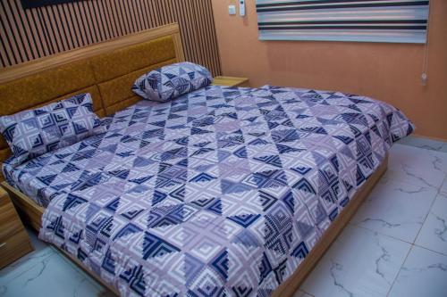a bedroom with a bed with a blue and white quilt at draysapartments in Ibadan