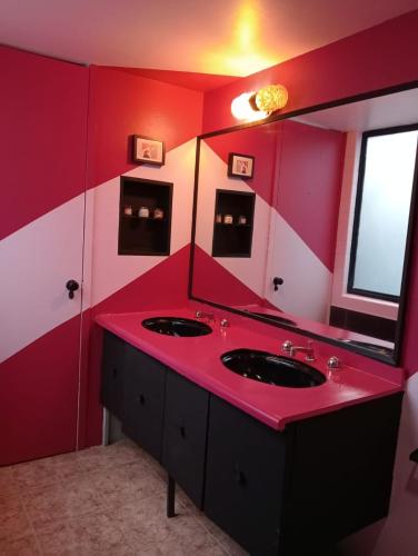 a red bathroom with two sinks and a mirror at Posada Bugambilia in Mexico City