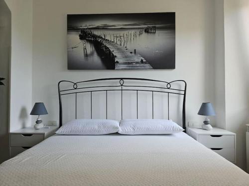 Casa Arcobaleno - giardino e parcheggio gratuito في لا سبيتسيا: غرفة نوم بسرير أبيض مع مصباحين ورصيف