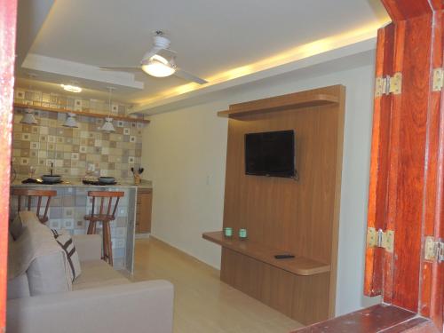 a living room with a couch and a tv on a wall at Pousada Portal de Búzios in Armacao dos Buzios
