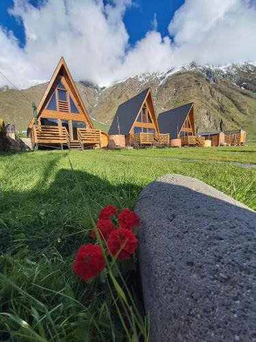a log cabin with flowers in front of it at Kazbegi Spa Resort Cottages in Stepantsminda