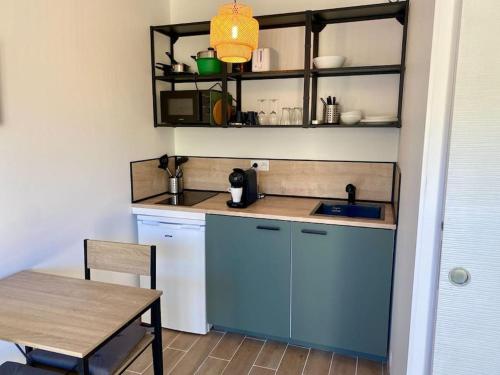 une petite cuisine avec des placards bleus et une table dans l'établissement studio avec terrasse, à La Londe-les-Maures