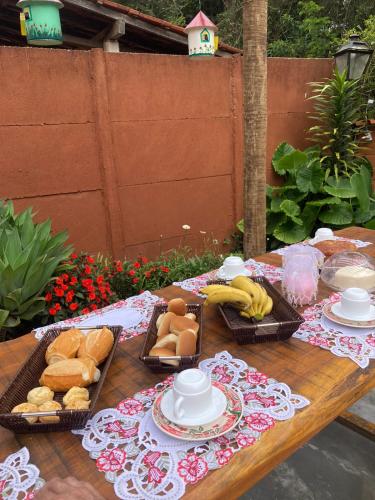 a table with baskets of bread and bananas on it at Pousada casa de fadas in Tiradentes