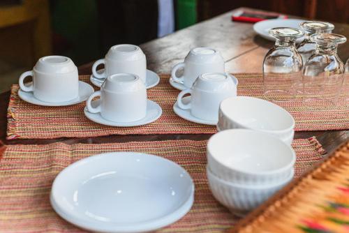 a table topped with white plates and cups and saucers at Pousada casa de fadas in Tiradentes