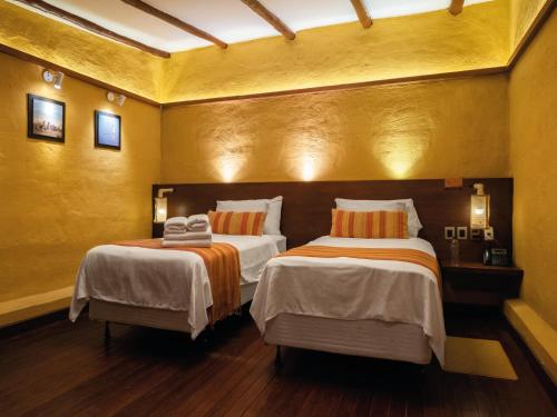 two beds in a room with yellow walls at Hotel Jardines de Uyuni in Uyuni