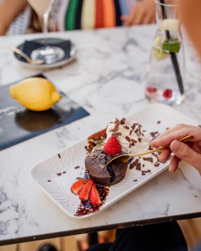a person eating a chocolate dessert with strawberries on a plate at GRAND CENTRAL LJUTOMER in Ljutomer