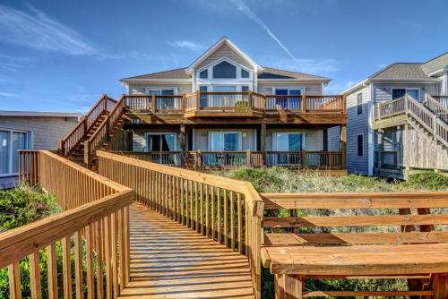 een huis met een houten loopbrug ervoor bij Barefoot Bungalow in Surf City