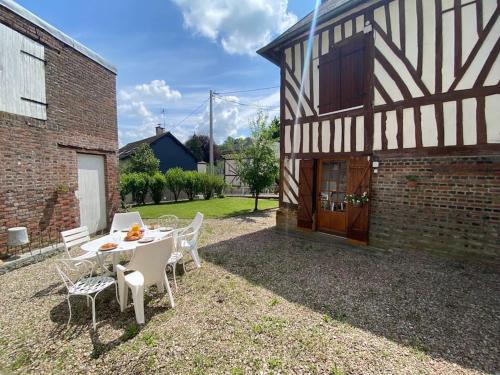 un patio avec une table et des chaises devant un bâtiment dans l'établissement La Halte de la Hunière, à Vimoutiers