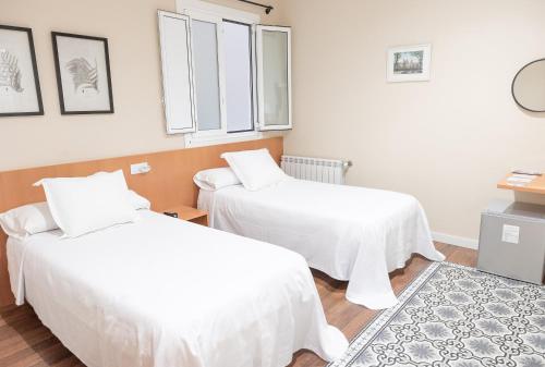 two beds in a room with white sheets at Hotel Montes in Santiago de Compostela